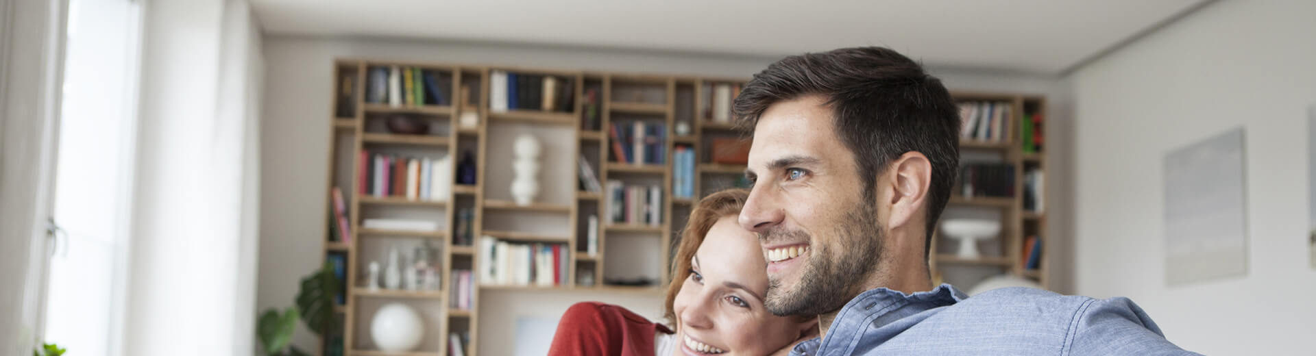 Chriscon Immobilien & Relocation Kaufen in München. Junges Paar im Wohnzimmer auf der Immobiliensuche.